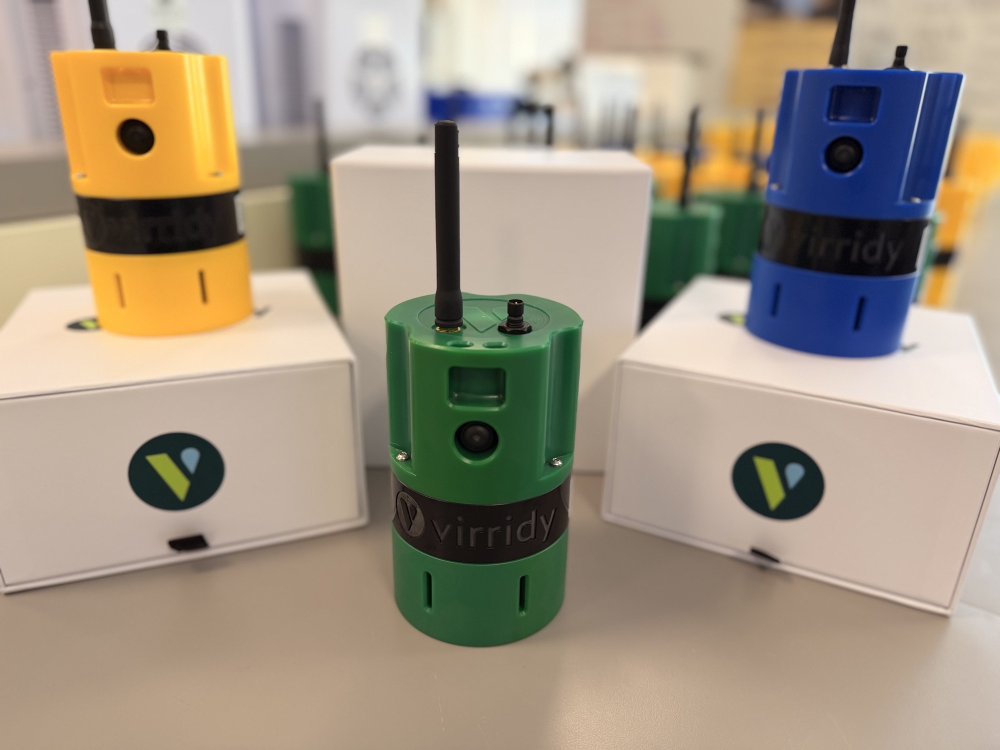Lume water-quality sensors in yellow, green and blue, shown with Virridy shipping boxes ready for deployment